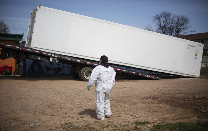 In this April 7, 2020 file photo, gravedigger Thomas Cortez watches as a refrigerated trailer is delivered to keep pace with a surge of bodies arriving for burials at the Hebrew Free Burial A