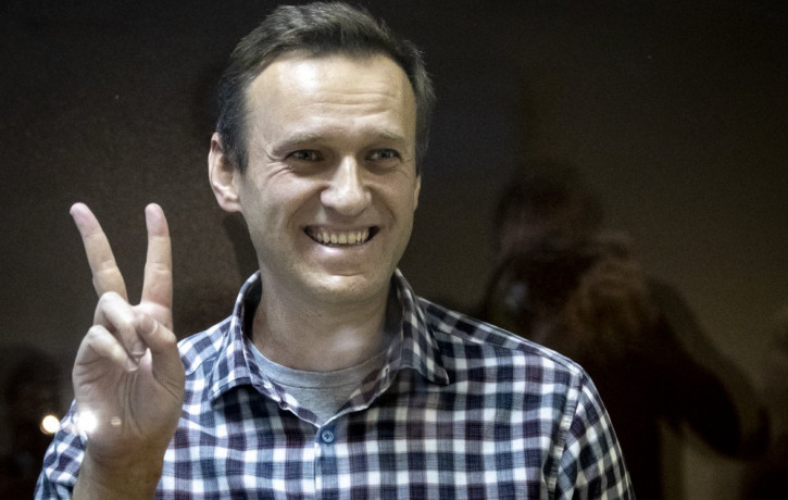 Russian opposition leader Alexei Navalny gestures as he stands behind a grass of the cage in the Babuskinsky District Court in Moscow, Russia, Saturday, Feb. 20, 2021.