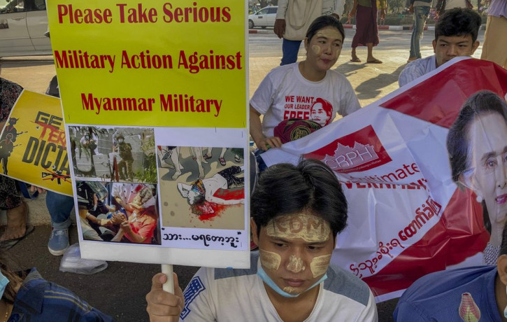 An anti-coup protester holds a placard requesting military action against Myanmar military in Yangon, Myanmar Thursday, Feb. 25, 2021.