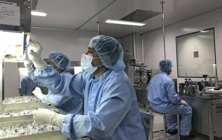 Production personnel perform a visual inspection of filled vaccine vials inside the Incepta plant on the outskirts of Dhaka in Bangladesh Saturday Feb. 13, 2021.