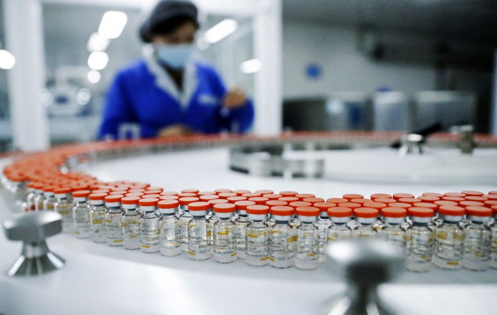 In this Dec. 23, 2020, file photo released by China's Xinhua News Agency, a Sinovac worker checks the labeling on vials of COVID-19 vaccines on a packaging line in Beijing.