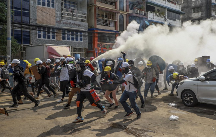 Anti-coup protesters run as one of them discharges a fire extinguisher to counter the impact of tear gas fired by riot policemen in Yangon, Myanmar, Wednesday, March 3, 2021.