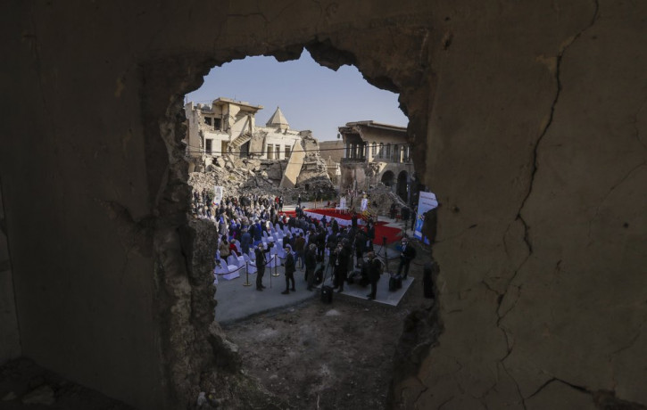 Surrounded by shells of destroyed buildings people arrive to join Pope Francis who will pray for the victims of war at Hosh al-Bieaa Church Square, in Mosul, Iraq, once the de-facto capital o