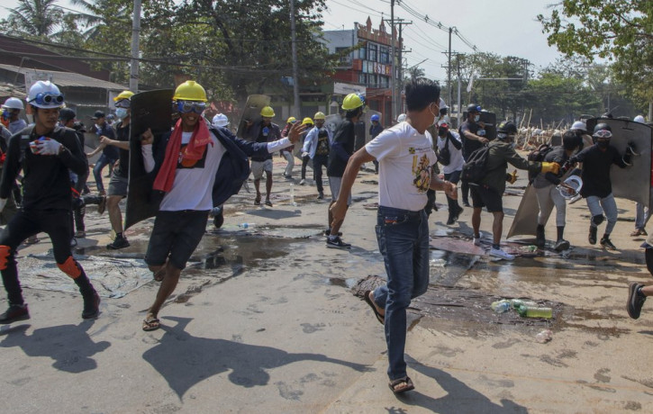 Anti-coup protesters retreat from the frontlines after riot policemen fire sound-bombs and rubber bullets in Yangon, Myanmar, Thursday, March 11, 2021.
