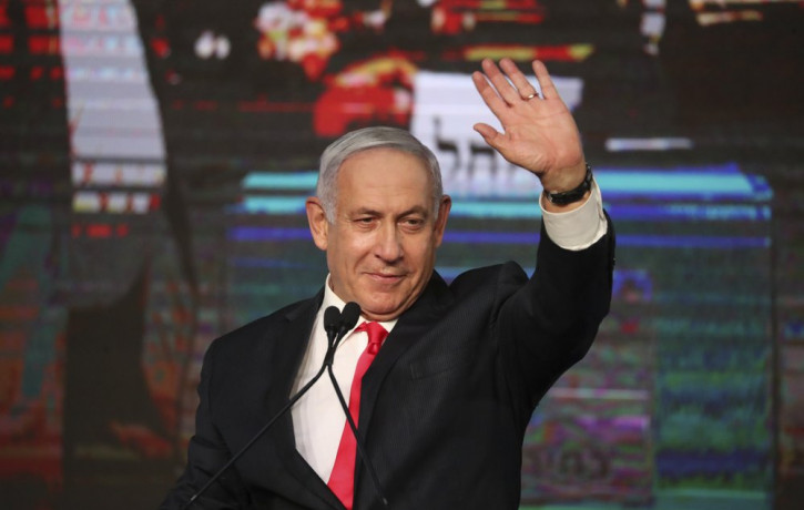 Israeli Prime Minister Benjamin Netanyahu waves to his supporters after the first exit poll results for the Israeli parliamentary elections at his Likud party's headquarters in Jerusalem, Wed