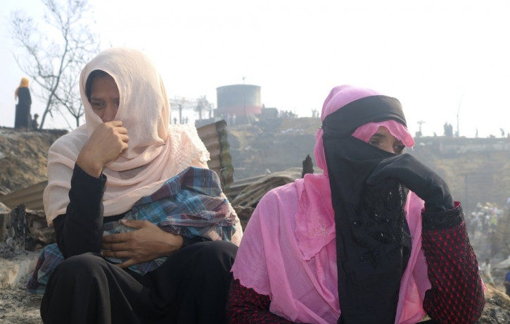 Rohingya refugees cry sitting at the site of Monday's fire at a refugee camp in Balukhali, southern Bangladesh, Tuesday, March 23, 2021.
