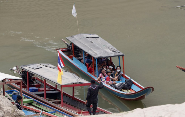 In this March 30, 2021, file photo, Karenni villagers from Myanmar arrive on a boat with an injured person as they evacuate to Ban Mae Sam Laep Health Center in Mae Hong Son province, norther