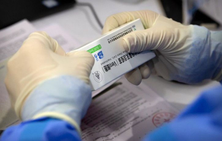 A worker opens a package of coronavirus vaccine made by a Sinopharm subsidiary during a COVID-19 vaccination session for resident foreign journalists at a vaccination center in Beijing, Tuesd