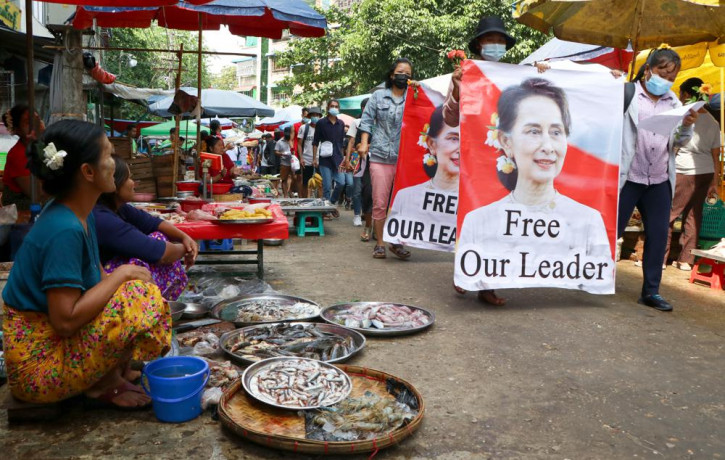 In this April 8, 2021, file photo, anti-coup protesters walk through a market with images of ousted Myanmar leader Aung San Suu Kyi in Yangon, Myanmar.