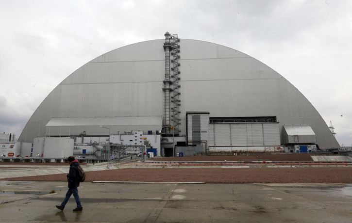 A man walks past a shelter covering the exploded reactor at the Chernobyl nuclear plant, in Chernobyl, Ukraine, Thursday, April 15, 2021.