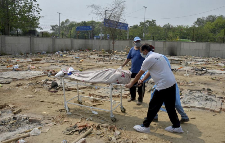 Body of a COVID-19 victim is wheeled in a ground that has been converted into a crematorium in New Delhi, India, Saturday, May 1, 2021.