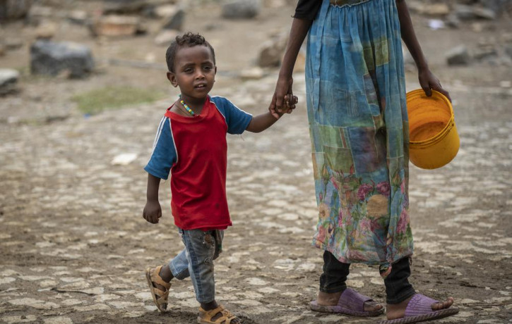 A displaced Tigrayan boy walks with a relative to receive food at the Hadnet General Secondary School which has become a makeshift home to thousands displaced by the conflict, in Mekele, in t