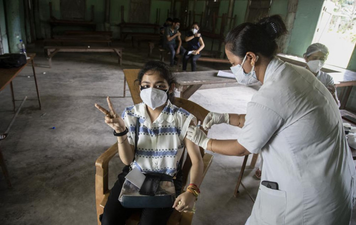 An Indian woman getting vaccinated with a dose of COVAXIN against the coronavirus gestures to camera in Gauhati, Assam, India, Monday, May 10, 2021.