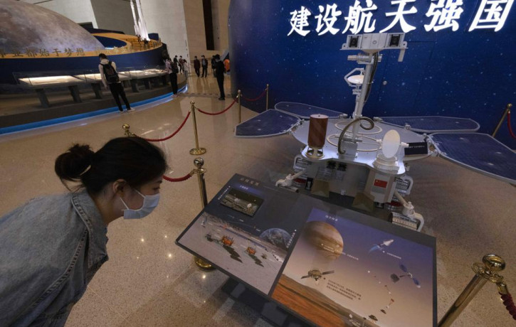 A visitor to an exhibition on China's space program looks at a life size model of the Chinese Mars rover Zhurong, named after the Chinese god of fire, at the National Museum in Beijing on Thu
