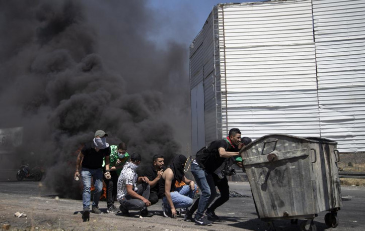 Palestinian demonstrators take cover during clashes with Israeli forces at the Hawara checkpoint, south of the West Bank city of Nablus, Friday, May 14, 2021.