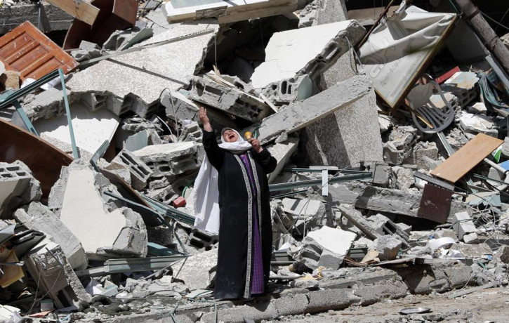 A woman reacts while standing near the rubble of a building that was destroyed by an Israeli airstrike on Saturday that housed The Associated Press, broadcaster Al-Jazeera and other media out