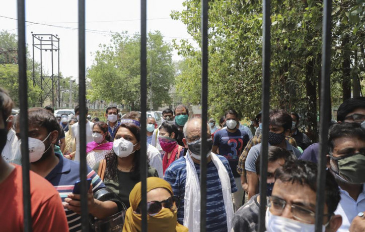 In this May 10, 2021, file photo, people waiting to get vaccinated against the coronavirus stand outside the closed gates of a hospital in Ghaziabad, outskirts of New Delhi, India.