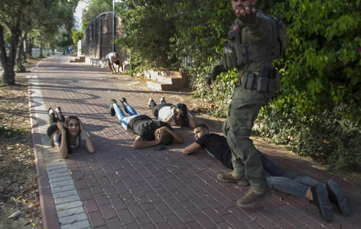 Israelis take cover as a siren sounds a warning of incoming rockets fired from the Gaza Strip, in Ashkelon, southern Israel, Sunday, May 16, 2021.