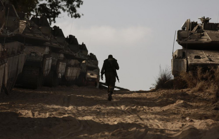 An Israeli soldier walks at a staging ground near the border with the Gaza Strip, in southern Israel, Thursday, May 20, 2021.