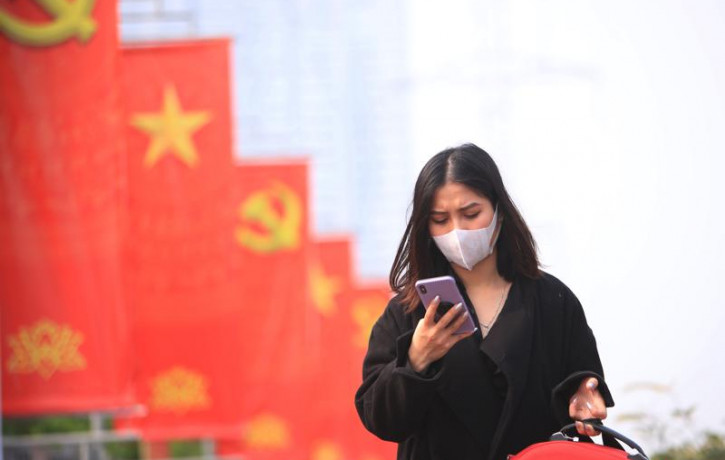 In this Jan. 23, 2021 file photo, a woman wearing face mask looks at her phone in Hanoi, Vietnam.