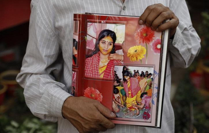 Radha Gobindo Pramanik holds photographs of his daughter who died of COVID-19 in Lucknow, India, Thursday, June 3, 2021.