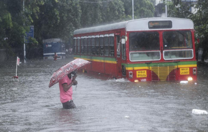 A man makes his way across a flooded street during heavy rains in Mumbai, India, Wednesday, June 9, 2021.