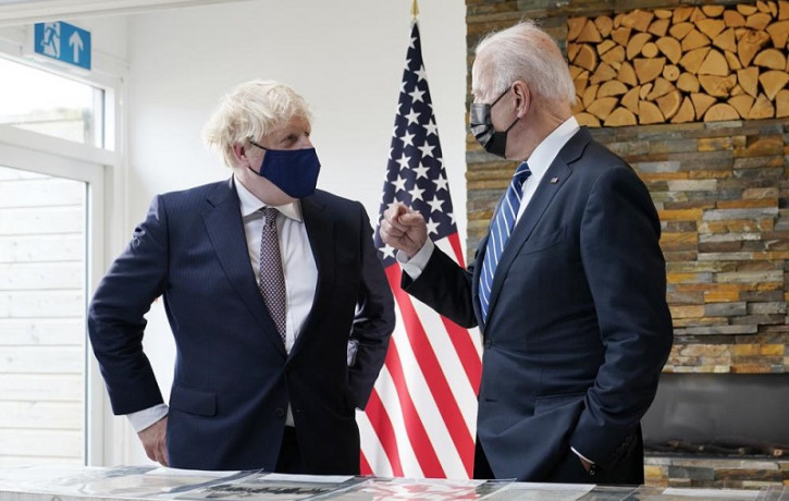 President Joe Biden and British Prime Minister Boris Johnson talk as they look over copies of the Atlantic Charter, during a bilateral meeting ahead of the G-7 summit, Thursday, June 10, 2021