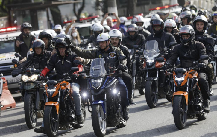 Brazil's President Jair Bolsonaro, center, waves as he leads a caravan of motorcycle enthusiasts following him through the streets of the city, in a show of support for Bolsonaro, in Sao Paul