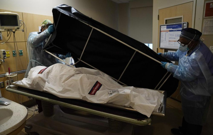 In this Jan. 9, 2021 file photo, transporters Miguel Lopez, right, Noe Meza prepare to move a body of a COVID-19 victim to a morgue at Providence Holy Cross Medical Center in the Mission Hill