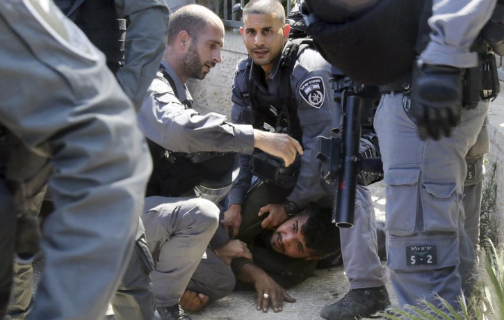 Israeli police officers detain a Palestinian man during clashes that erupted ahead of a planned march by Jewish ultranationalists through east Jerusalem, outside Jerusalem's Old City, Tuesday