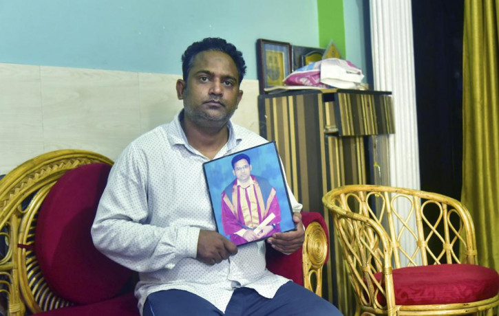 A relative holds a photograph of Dr. Jibraeil, assistant professor of history at Aligarh Muslim Uliversity, who died of COVID-19, in Aligarh, India, Saturday, June 12, 2021.