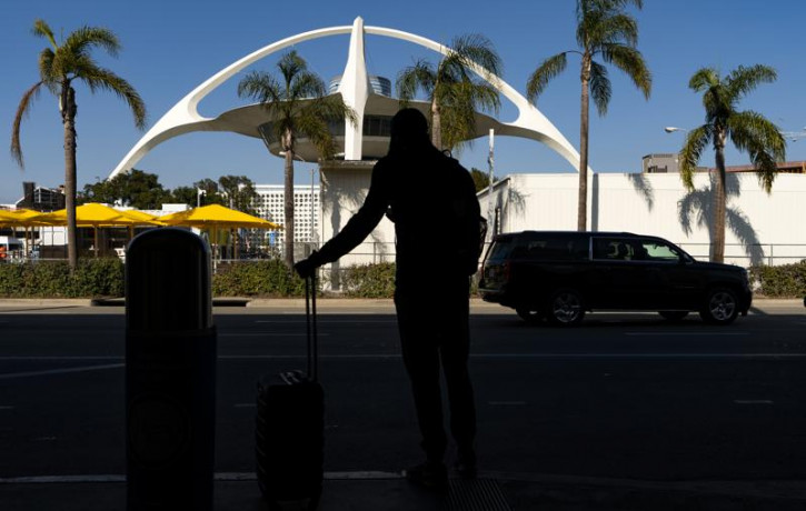 In this Nov. 25, 2020, file photo, a traveler awaits for transportation at the Los Angeles International Airport in Los Angeles.