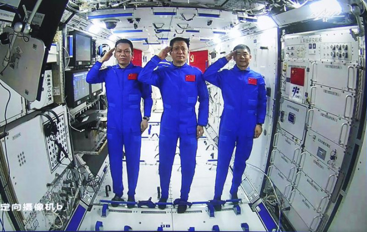 Chinese astronauts, from left; Tang Hongbo, Nie Haisheng, and Liu Boming salute from aboard China's space station core module Tianhe during a video conversation with Chinese President Xi Jinp