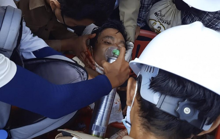 In this Sunday, Feb. 28, 2021 image from video provided by Dakkhina Insight, medics attend to a man who appeared to be wounded in his upper chest on a street in Dawei, Myanmar.