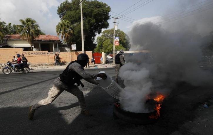 Police put out a burning tire set fire by protesters upset with growing violence in the Lalue neighborhood of Port-au-Prince, Haiti, Wednesday, July 14, 2021.