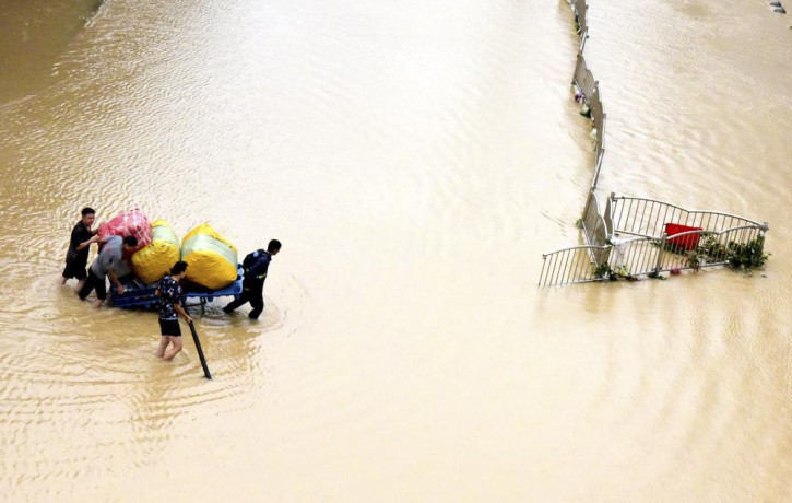 In this photo released by Xinhua News Agency, residents move their belongings across a flooded street in Zhengzhou in central China's Henan province on Wednesday, July 21, 2021.