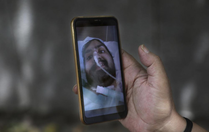 Anil Sharma shows a photograph of his son Saurav who is being treated for COVID-19 at a private hospital in New Delhi, India, Thursday, July 1, 2021.
