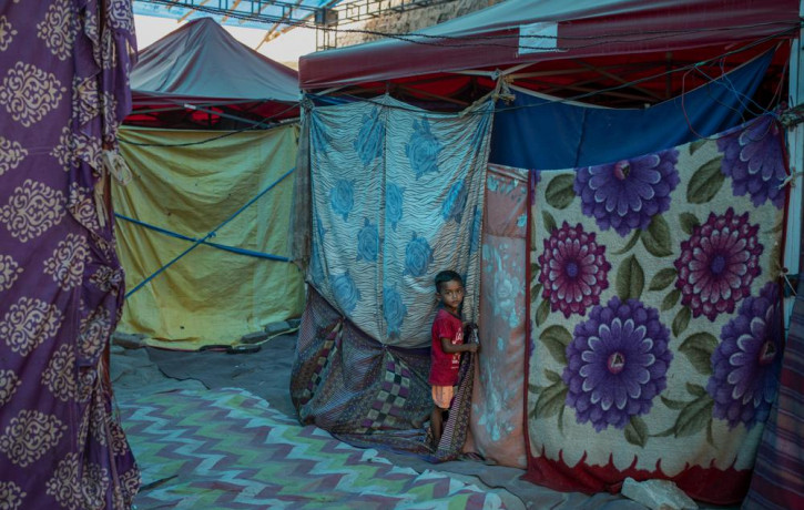 A young Rohingya refugee boy stands outside a tent at a refugee camp alongside the banks of the Yamuna River in the southeastern borders of New Delhi, sprawling Indian capital, July 1, 2021.