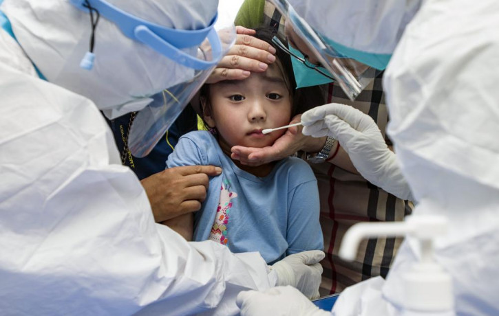 A child reacts to a throat swab during mass testing for COVID-19 in Wuhan in central China's Hubei province Tuesday, Aug. 3, 2021.
