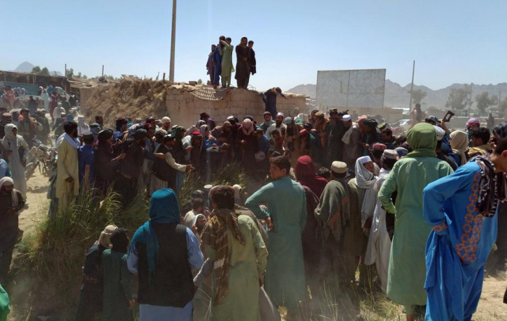 Taliban fighters and Afghans gather around the body of a member of the security forces who was killed, inside the city of Farah, capital of Farah province, southwest Afghanistan, Wednesday, A