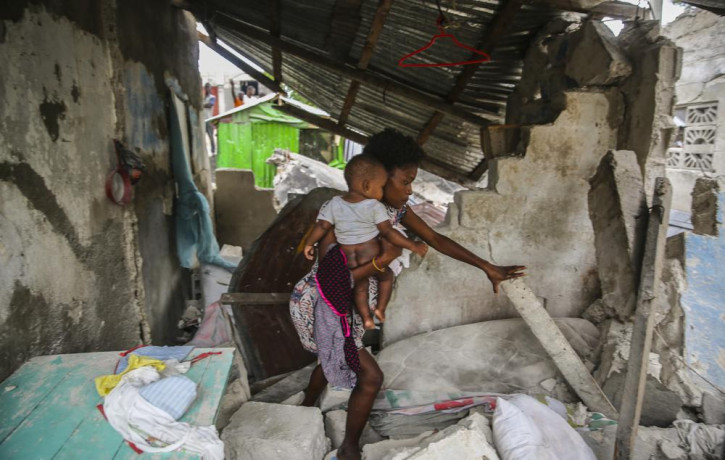 A woman carries her child as she walks in the remains of her home destroyed by Saturday´s 7.2 magnitude earthquake in Les Cayes, Haiti, Sunday, Aug. 15, 2021.