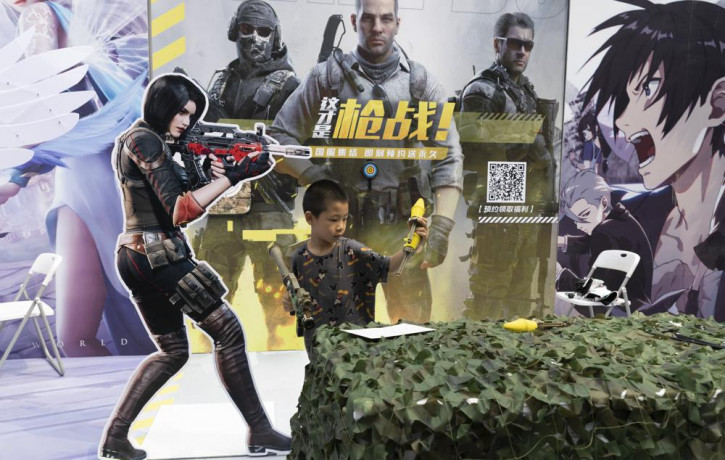A child plays with a toy gun during a promotion for online games in Beijing on Saturday, Aug. 29, 2020.