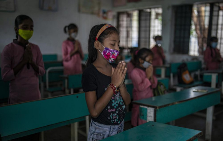 School children attend morning assembly inside a classroom on the first day of partial reopening of schools in Noida, a suburb of New Delhi, India, Wednesday, Sept. 1, 2021.