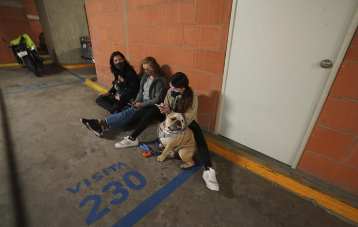 People gather outside thier building with their pet after a strong earthquake, in Mexico City, Tuesday, Sept. 7, 2021.