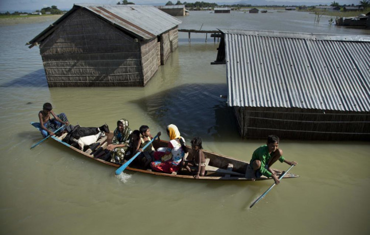 In this July 31, 2016, file photo, a flood-affected family with their goats travel on a boat in the Morigaon district, east of Gauhati, northeastern Assam state, India.
