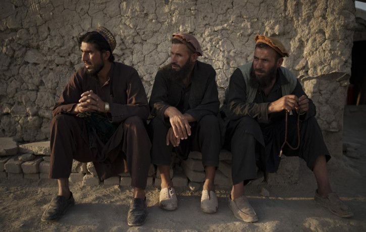 Afghans sit outside a mosque in a poor neighborhood where hundreds of internally displaced people from the eastern part of the country have been living for years, in Kabul, Afghanistan, Monda