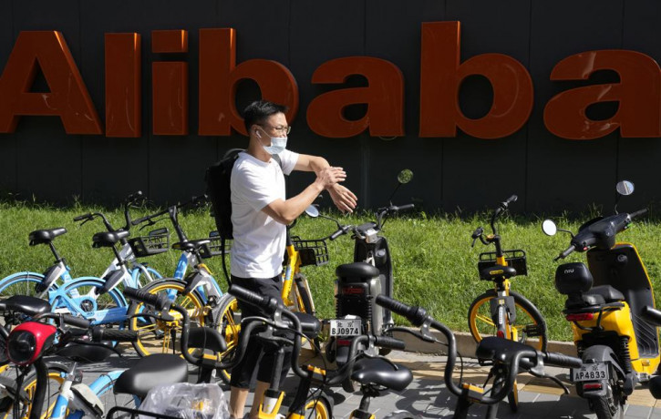 A man passes by the logo for Alibaba outside the Beijing headquarters in Beijing, China, Tuesday, Aug. 24, 2021.
