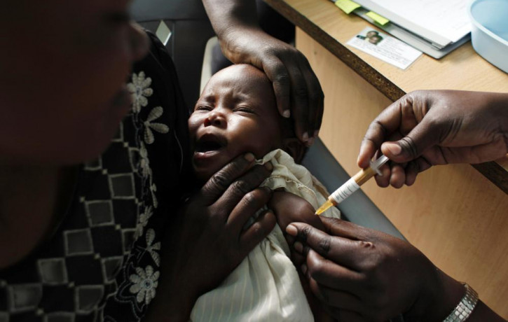 In this Oct. 30, 2009 file photo, a mother holds her baby receiving a new malaria vaccine as part of a trial at the Walter Reed Project Research Center in Kombewa in Western Kenya.