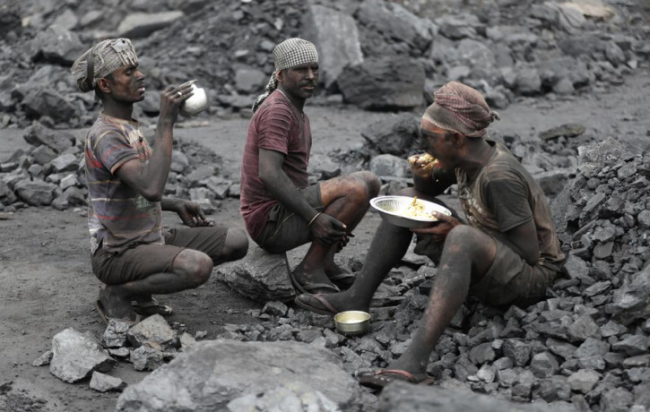 In this Oct. 23, 2019, file photo, laborers eat lunch at a coal loading site in the village of Godhar in Jharia, a remote corner of eastern Jharkhand state, India.