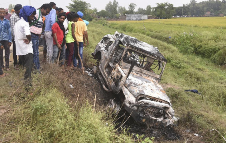 Villagers watch a burnt car which ran over and killed farmers on Sunday, at Tikonia village in Lakhimpur Kheri, Uttar Pradesh state, India, Monday, Oct. 4, 2021.